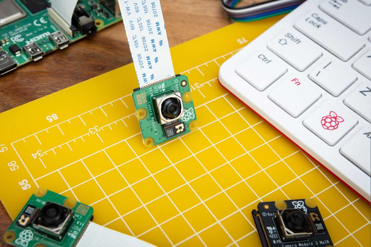 Raspberry Pi Camera Module 3 on a workbench with a ribbon cable